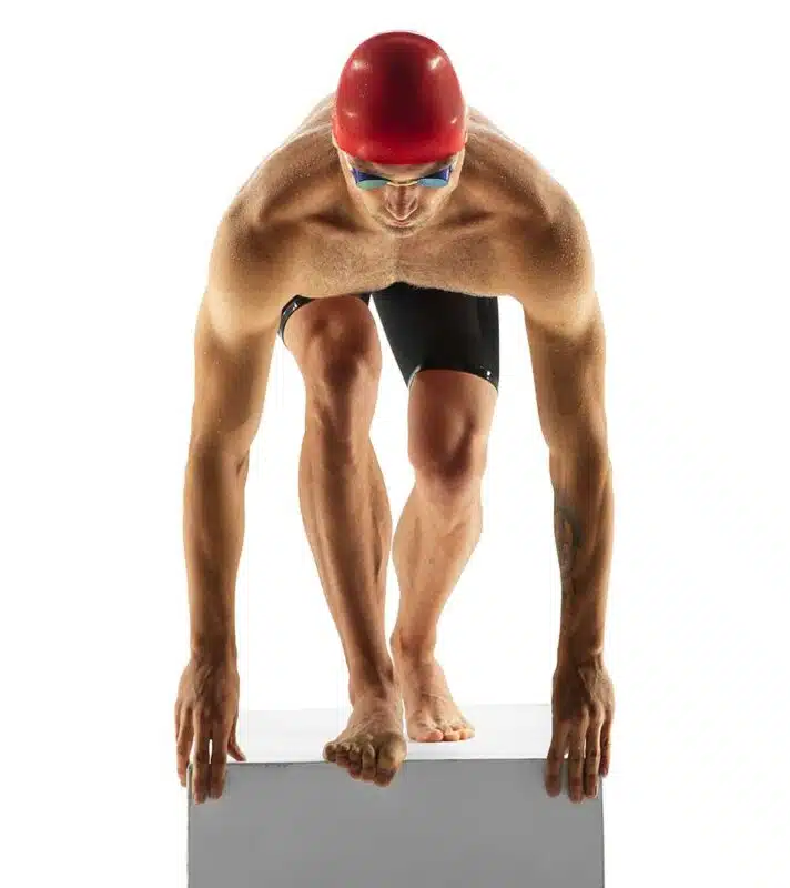 Nageur sur le tremplin, prêt à plonger pour une course, illustrant la catégorie des médailles de natation personnalisées.
